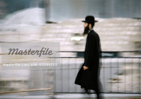Israel, Jerusalem, Orthodox Jew walking by barrier, side view, blurred
