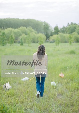 Woman walking in field strewn with plastic bags