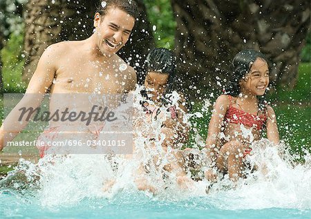 Father and children splashing in swimming pool