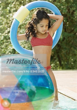Girl in swimming pool, holding ring over head