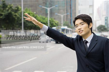 Young businessman hailing at taxi