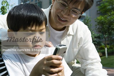 Father and son, boy looking at cell phone