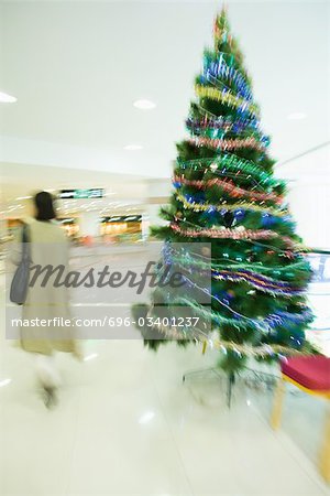Female shopper walking past Christmas tree in mall