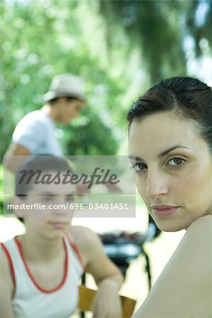 Family having cookout, woman looking over shoulder at camera