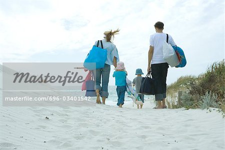 Famille plage a pied à travers les dunes