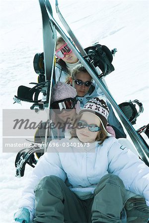 Jeunes skieurs assis dans la neige skis portrait sur la tête, soutenu vers le haut