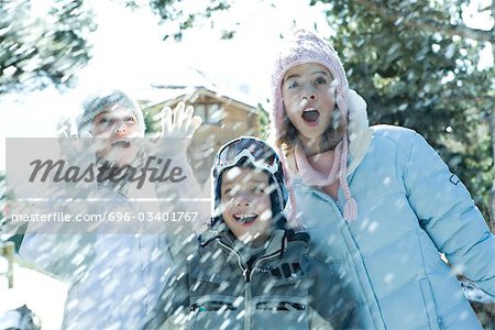 Jeunes amis debout dans la neige qui tombe, souriant, taille