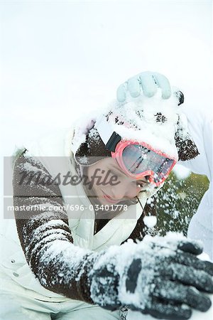 Teenage girl in snowball fight, bending over