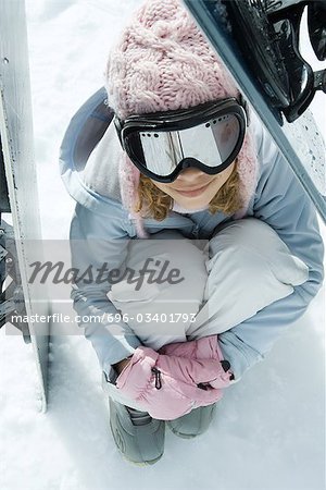 Préados fille assise sur la neige calé en-dessous de planches à neige, vue grand angle