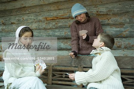 Junge Freunde der Spielkarten im Freien, in Winterkleidung gekleidet
