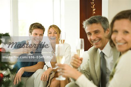 Adultes amis faire un toast au champagne, souriant à la caméra