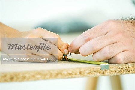 Couple measuring wood, cropped view of hands