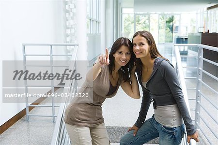 Femme debout dans un escalier avec une fille, pointage, les deux à la recherche et souriant