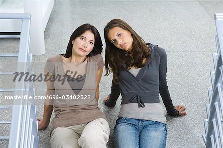 Mère et fille assis ensemble sur le terrain, les deux regardant vers le haut appareil-photo