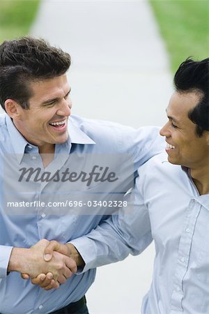 Two businessmen shaking hands, both smiling, high angle view