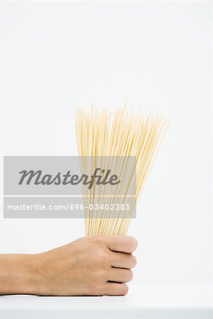 Woman holding handful of dried pasta, cropped view of hand