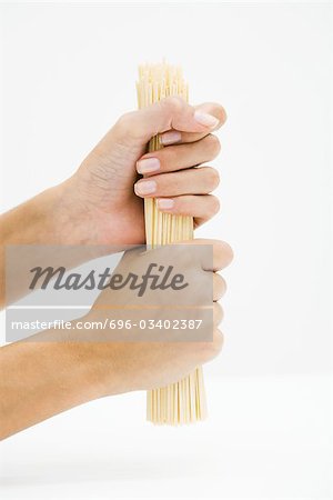 Woman holding dried pasta, cropped view of hands