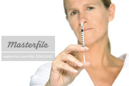 Woman holding up syringe, looking at camera