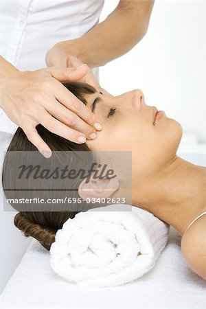 Woman receiving head massage, lying down with her eyes closed, cropped view