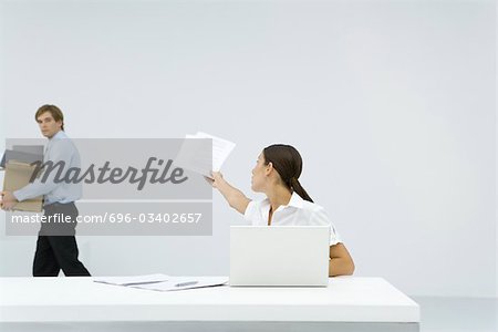 Femme assise au bureau, qui remontent à la main les documents d'homme portant une boîte