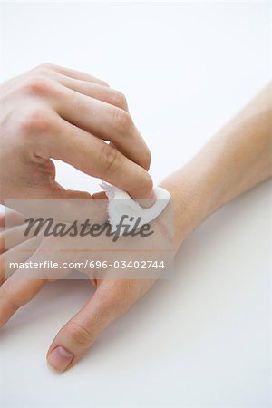 Person holding gauze against wounded hand, cropped view