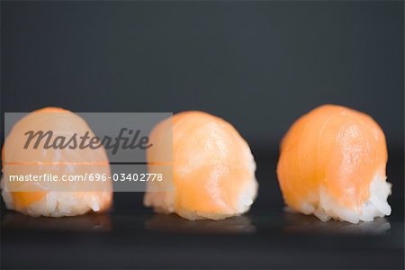 Three pieces of salmon nigiri sushi with dark background, close-up