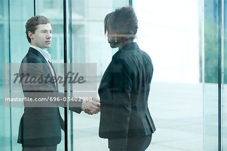 Businessman and businesswoman meet and shake hands at building entrance