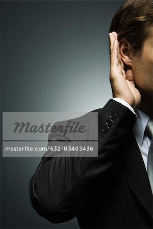 Man with hand cupped around ear listening attentively