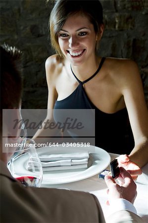 Young woman smiling at young man giving her a ring