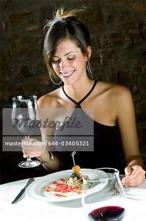 Jeune femme avec assiette de nourriture et vin au restaurant