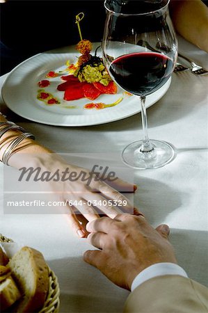 Closeup of couple's hands touching at dinner table