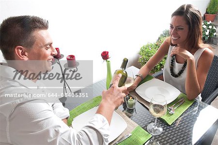 Young man pouring wine for young woman at restaurant table