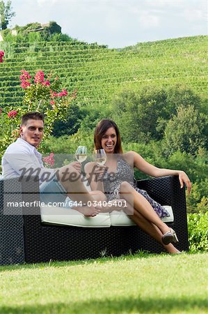 Jeune couple assis sur le canapé dans la vigne au vin blanc