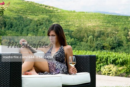 Jeune femme assise sur le canapé dans la vigne au vin blanc, lire un livre