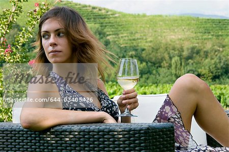 Jeune femme assise sur le canapé dans la vigne au vin blanc
