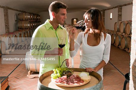 Couple in a wine cellar tasting red wine and antipasti