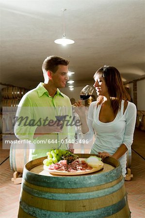 Couple in a wine cellar tasting red wine and antipasti