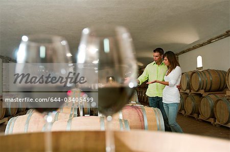 Couple dans une cave à vin avec verres de vin rouge