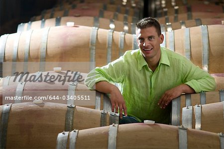 Young man in wine cellar with wooden barrels