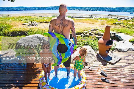 man with kids in wading pool near beach