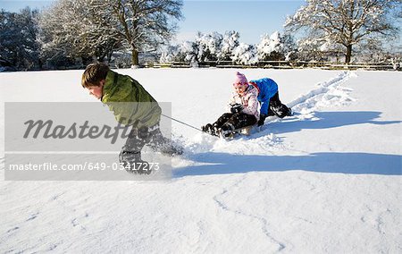 Kinder spielen auf Schlitten im Schnee