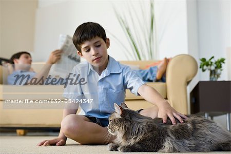 Junge sitzen im Wohnzimmer schmusen Katze