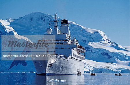 MV Discovery in Paradise Harbour with surrounding peaks and icebergs. Antarctic Peninsula.