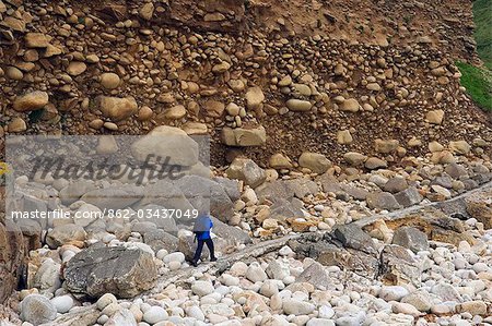 Un marcheur sur le sentier côtier Cornish promenades sous une falaise abrupte, montre des signes d'érosion côtière dans la vallée de Cot, Cornouailles, Angleterre