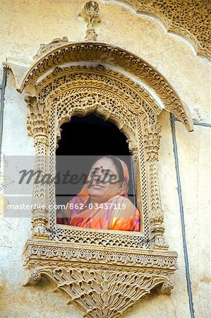 Inde, Rajasthan, Jaiselmer, Patwon ki Haveli. Lady habillée traditionnellement habillée ressemble d'une des fenêtres lourdement décorés dans celui en mieux Havelis préservé de la ville.