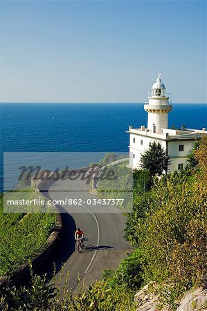 San Sebastian Bay Clifftop Lighthouse with Cyclist Riding uphill