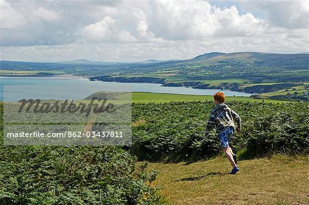 Au Royaume-Uni, pays de Galles, Pembrokeshire. Un garçon longe le sentier côtier du Pembrokeshire Dinas tête avec vue sur baie de Newport au-delà.