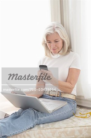 Woman at Home Using Laptop Computer and Sending Text Message