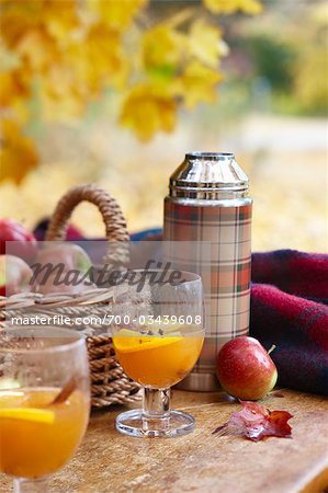 Thermosflasche mit Apfelwein und Korb mit Äpfeln