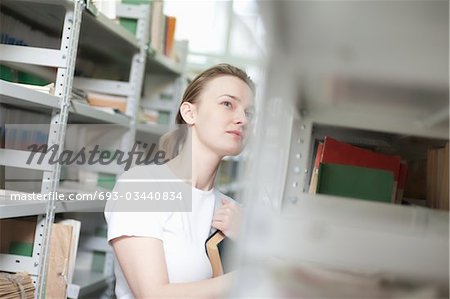 Young woman stands at library shelving